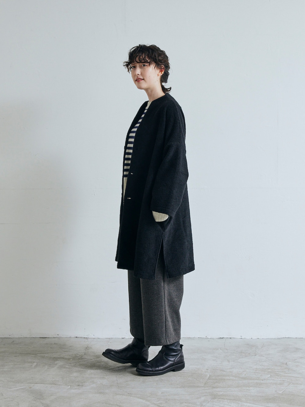 ブラック系のノーカラーコートを着用したレディースの秋コーディネートの2枚目の写真