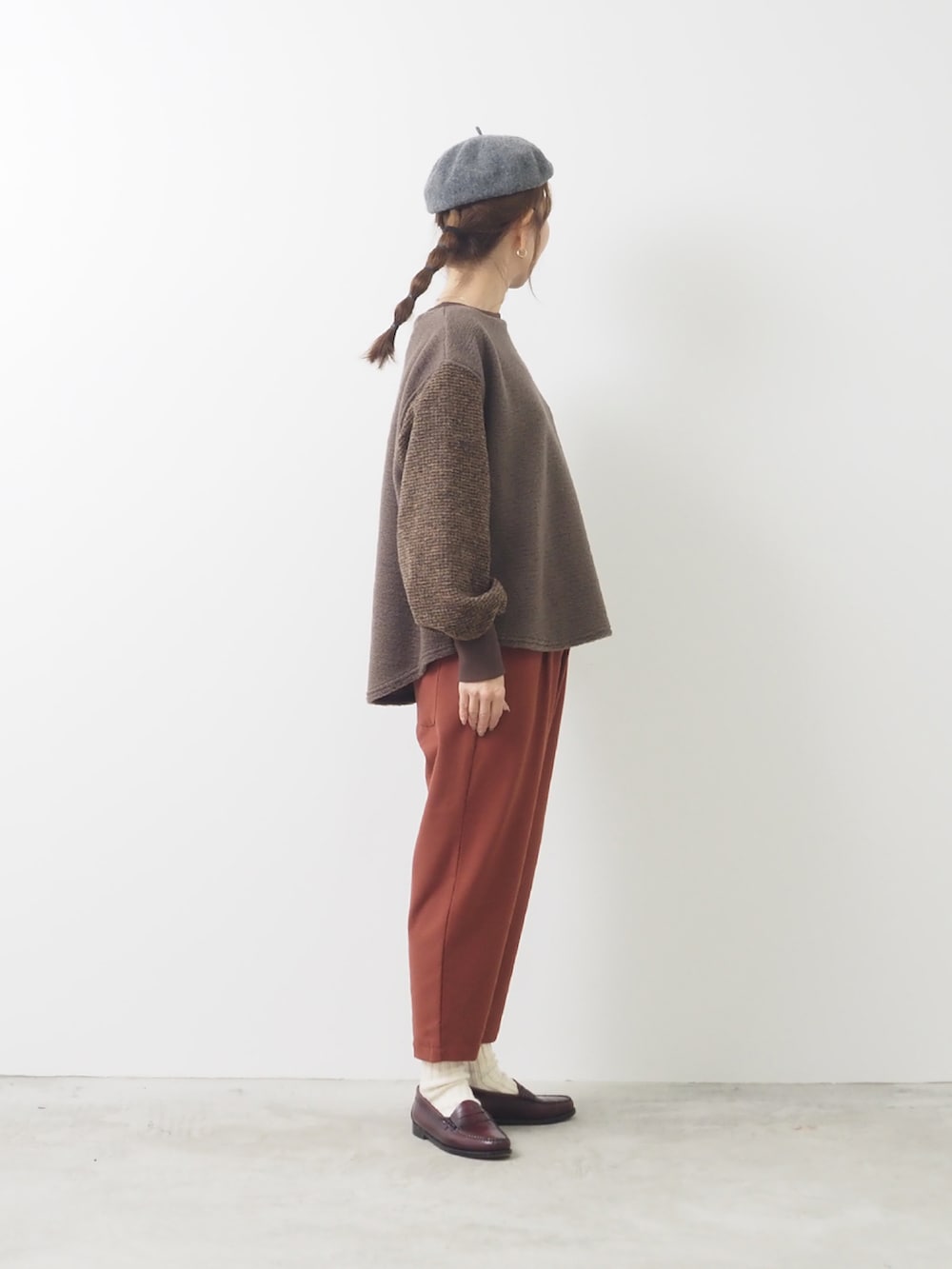 グレー系のトップス、レッド系のパンツを着用したレディースの秋コーディネートの2枚目の写真