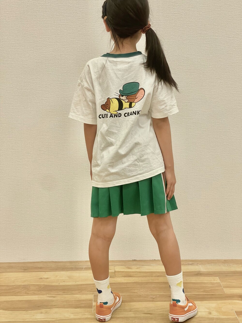 ホワイト系のTシャツ/カットソー、グリーン系のスカート、オレンジ系のスニーカーを着用したキッズの春コーディネートの3枚目の写真