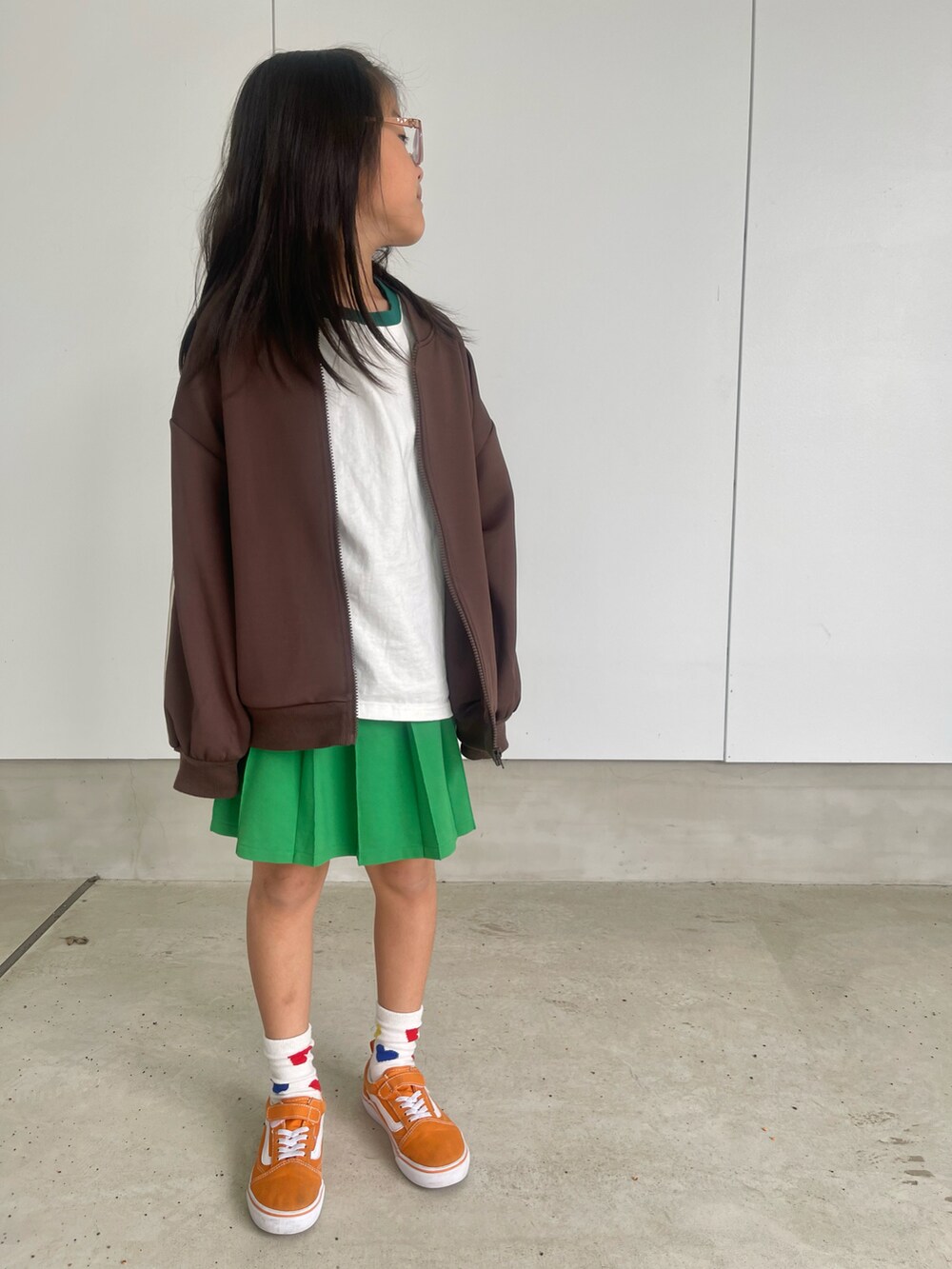 ホワイト系のTシャツ/カットソー、グリーン系のスカート、オレンジ系のスニーカーを着用したキッズの春コーディネートの2枚目の写真