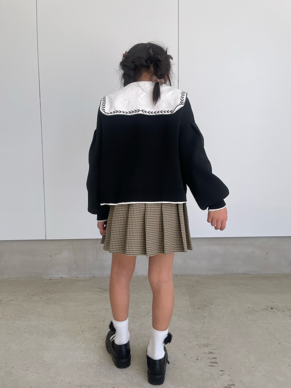 ブラック系のその他シューズ、ベージュ系のスカート、ブラック系のカーディガン/ボレロを着用したキッズの春コーディネートの2枚目の写真