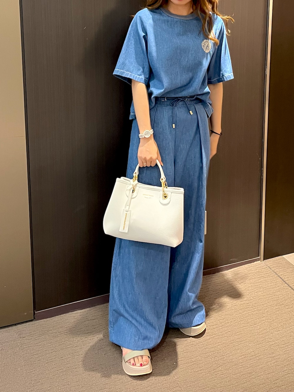 ブルー系のシャツ/ブラウス、ブルー系のデニムパンツ、ベージュ系のハンドバッグを着用したレディースの夏コーディネートの2枚目の写真