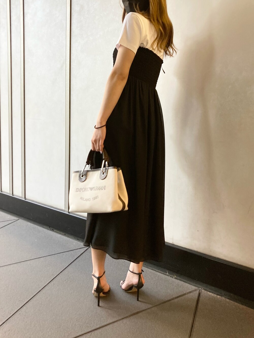 ブラック系のスカート、ベージュ系のハンドバッグ、ブラック系のサンダルを着用したレディースの夏コーディネートの3枚目の写真