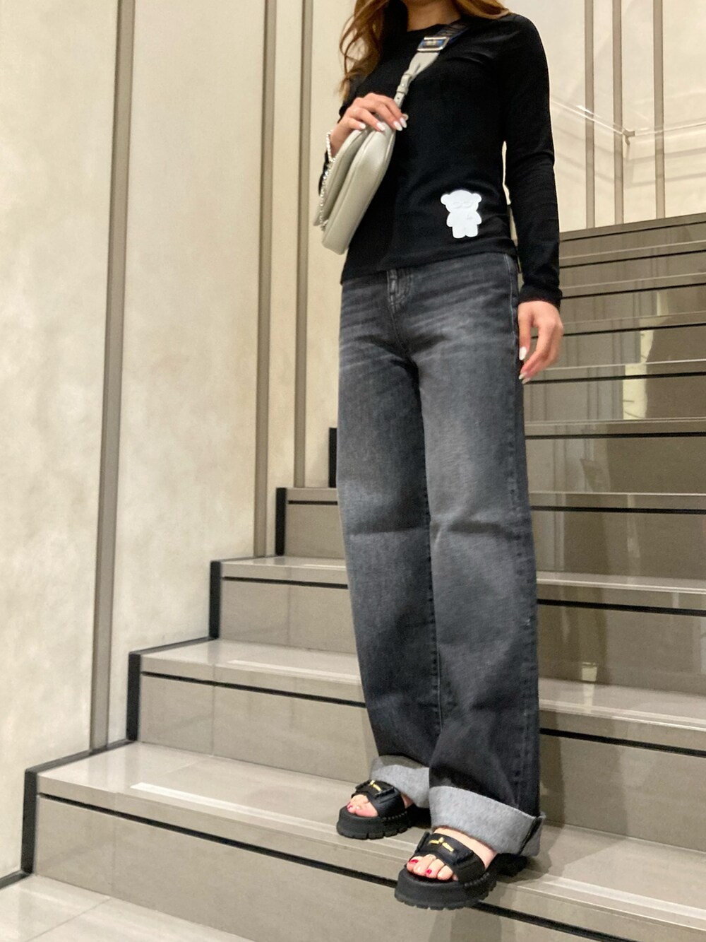 ブラック系のデニムパンツ、ブラック系のTシャツ/カットソー、グレー系のショルダーバッグを着用したレディースの夏コーディネートの2枚目の写真