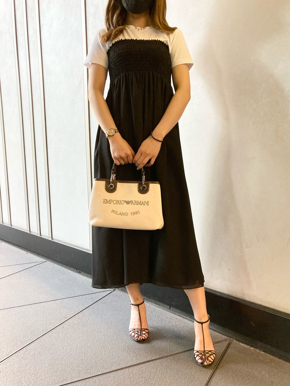 ブラック系のスカート、ベージュ系のハンドバッグ、ブラック系のサンダルを着用したレディースの夏コーディネートの2枚目の写真