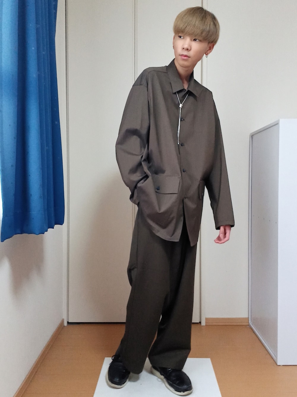 ブラウン系のブルゾン、ブラウン系のその他パンツ、ホワイト系のショルダーバッグを着用したメンズの冬コーディネートの2枚目の写真