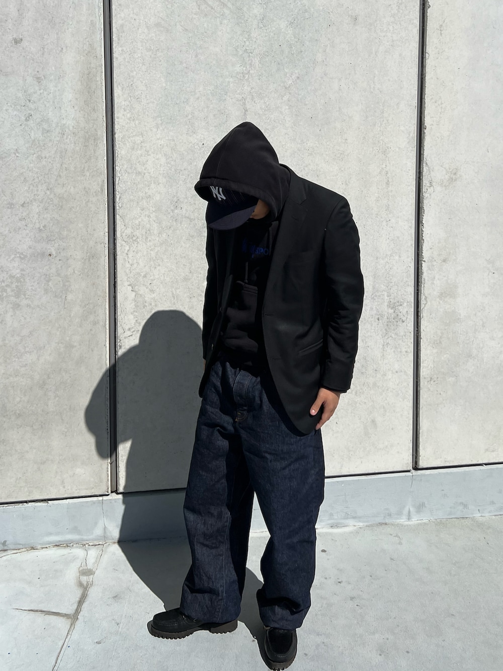 ブルー系のデニムパンツ、ブラック系のテーラードジャケット、ブラック系のパーカーを着用したメンズの春コーディネートの2枚目の写真