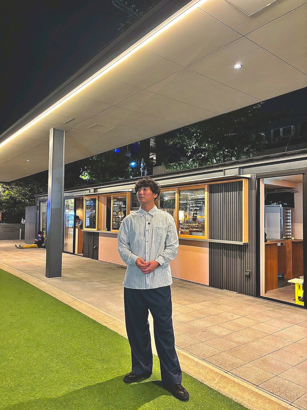 ブルー系のスラックス、ブラック系のスニーカー、グリーン系のシャツ/ブラウスを着用したメンズの秋コーディネートの3枚目の写真