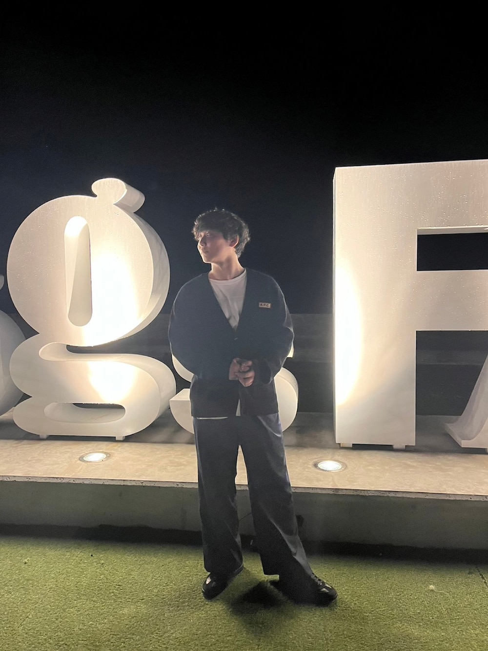 ブラック系のカーディガン/ボレロ、ブルー系のスラックス、ブラック系のスニーカーを着用したメンズの秋コーディネートの2枚目の写真