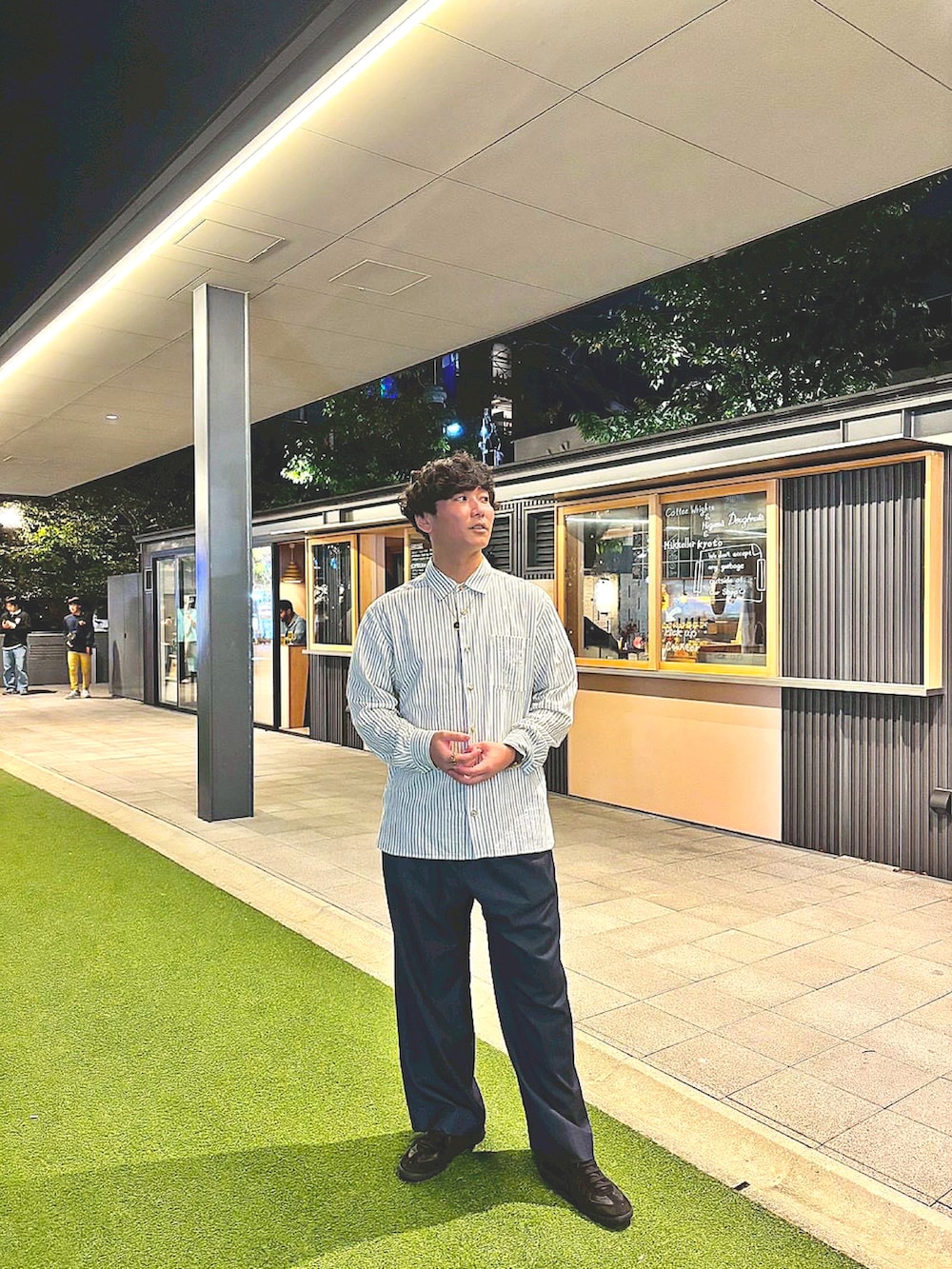 ブルー系のスラックス、ブラック系のスニーカー、グリーン系のシャツ/ブラウスを着用したメンズの秋コーディネートの2枚目の写真