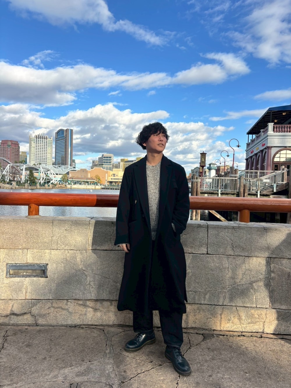 ブラック系のチェスターコート、ブルー系のデニムパンツ、ブラック系のドレスシューズを着用したメンズの春コーディネートの2枚目の写真