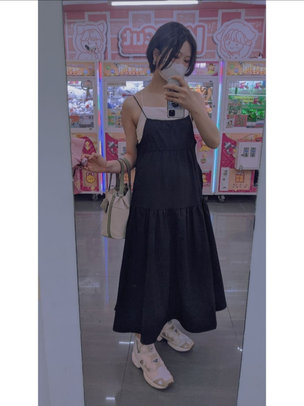 ベージュ系のスニーカー、ブラック系のワンピース、グリーン系のハンドバッグを着用したレディースの秋コーディネートの2枚目の写真