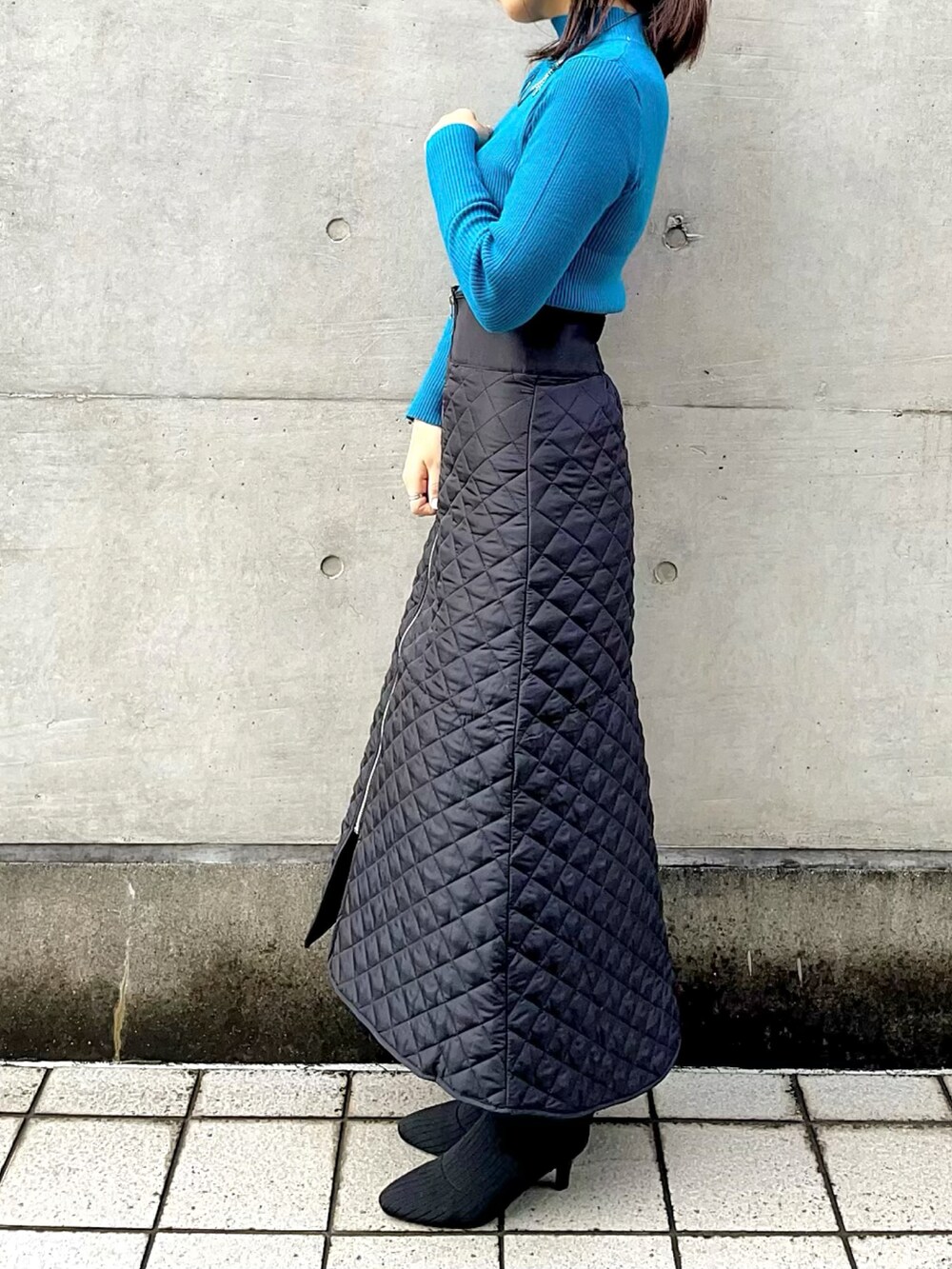 ブルー系のニット/セーター、ブラック系のパーカー、ブラック系のブーツを着用したレディースの秋コーディネートの2枚目の写真