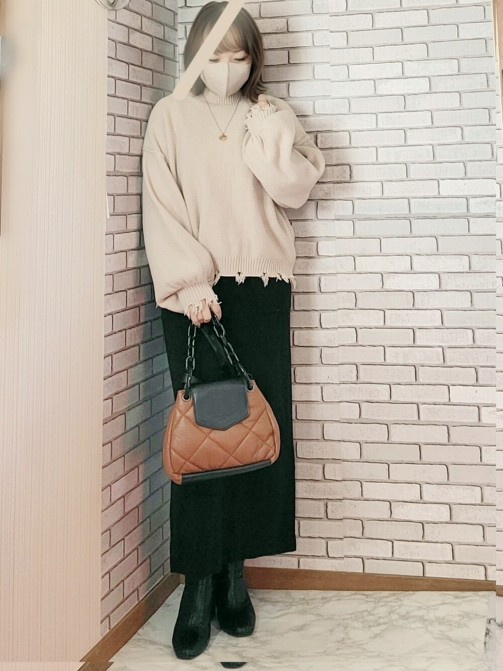 ベージュ系のニット/セーター、ブラック系のスカート、ブラック系のブーツを着用したレディースの冬コーディネートの2枚目の写真