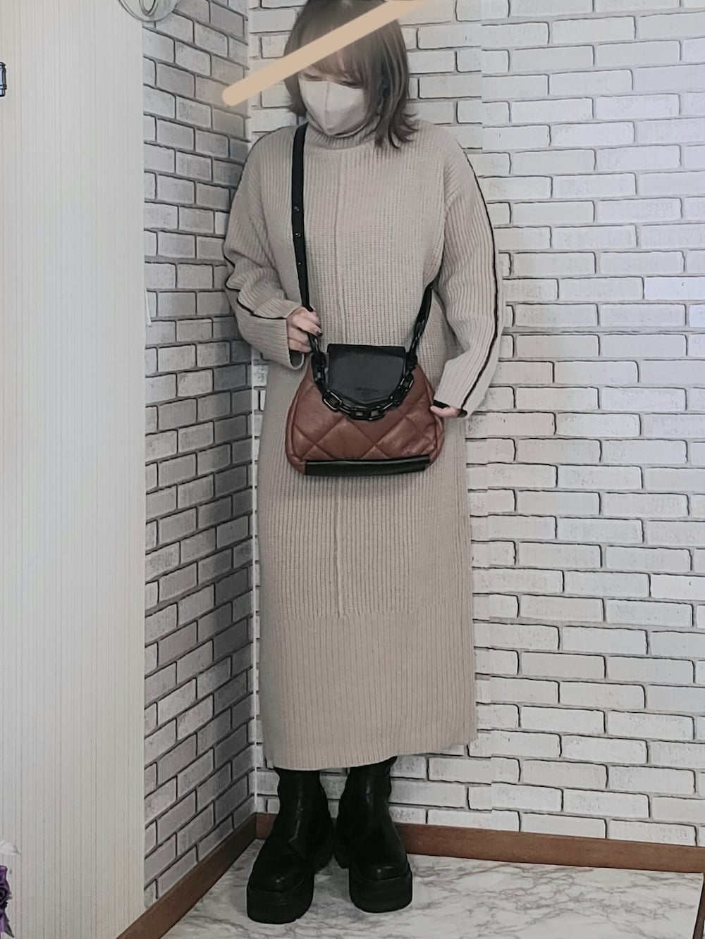 ブラック系のムートンコート、ベージュ系のワンピース、ブラック系のブーツを着用したレディースの秋コーディネートの2枚目の写真