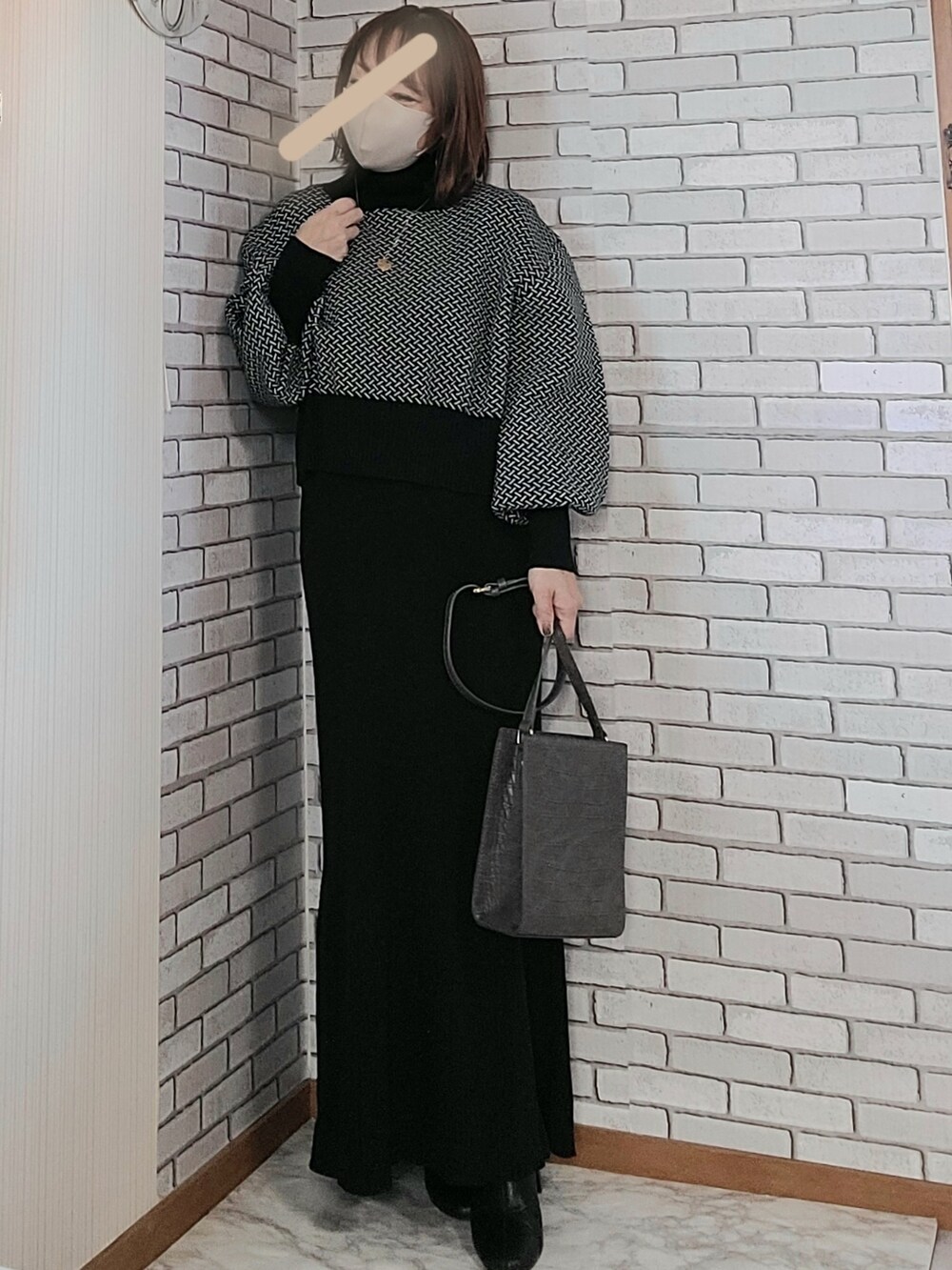 ブラック系のムートンコート、ブラック系のニット/セーター、ブラック系のワンピースを着用したレディースの秋コーディネートの2枚目の写真