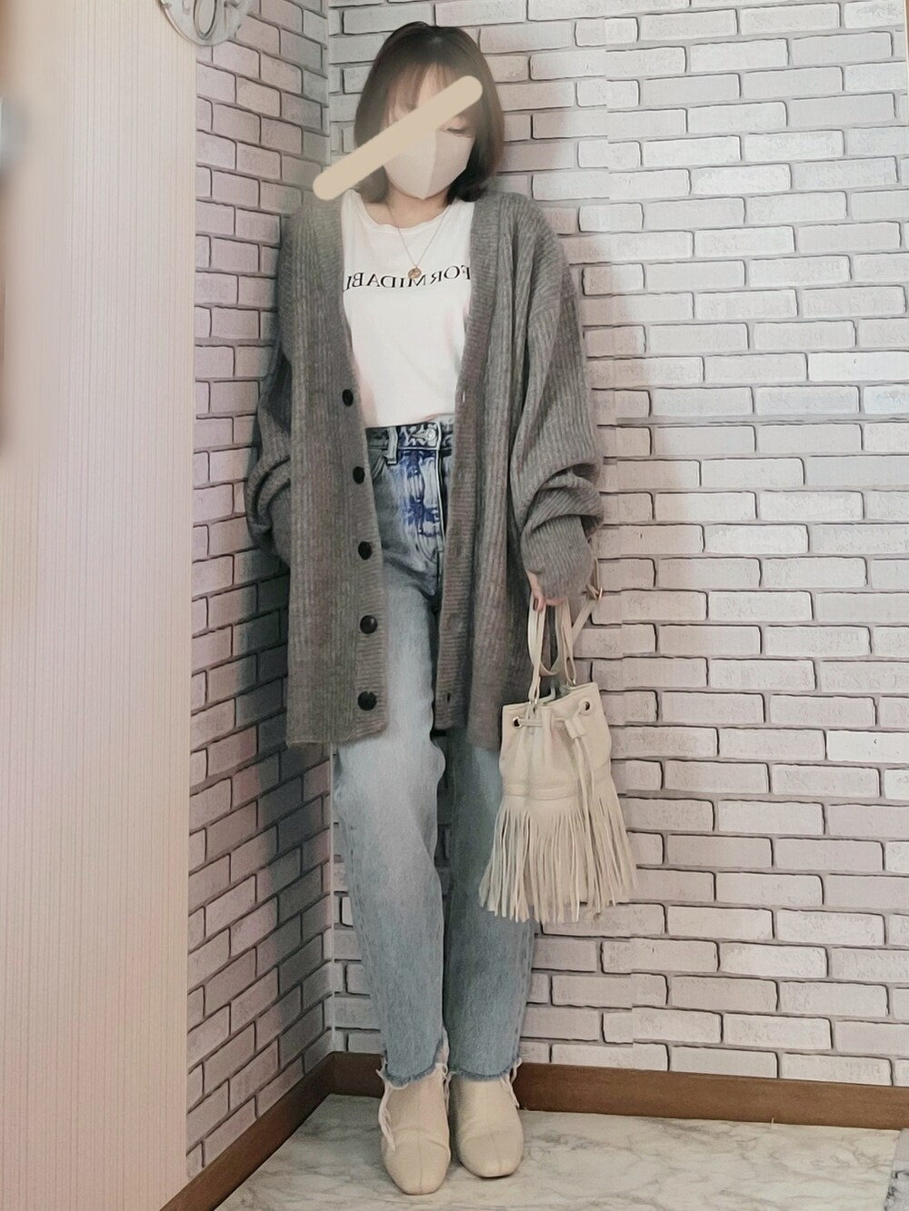 グレー系のカーディガン/ボレロ、ホワイト系のTシャツ/カットソー、ブルー系のデニムパンツを着用したレディースの冬コーディネートの2枚目の写真