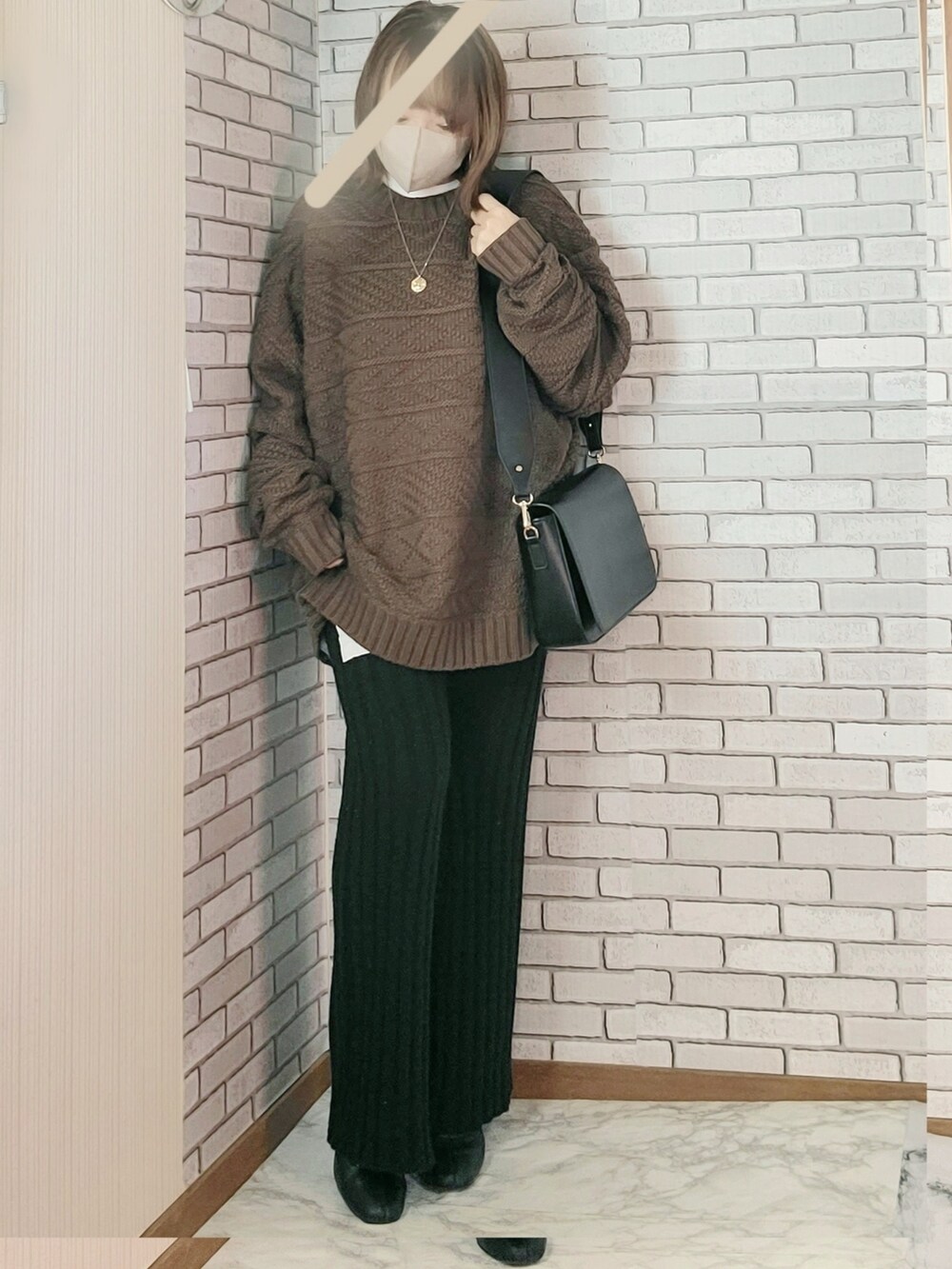 ブラック系のノーカラーコート、ブラウン系のニット/セーター、ホワイト系のTシャツ/カットソーを着用したレディースの冬コーディネートの2枚目の写真