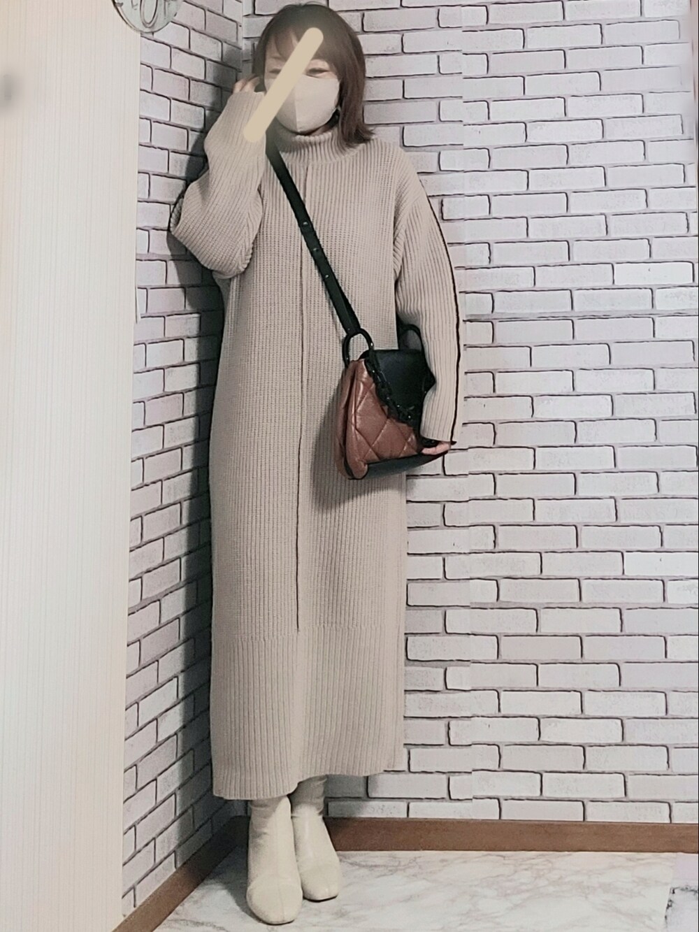 ブルー系のノーカラーコート、ベージュ系のワンピース、ホワイト系のブーツを着用したレディースの冬コーディネートの2枚目の写真