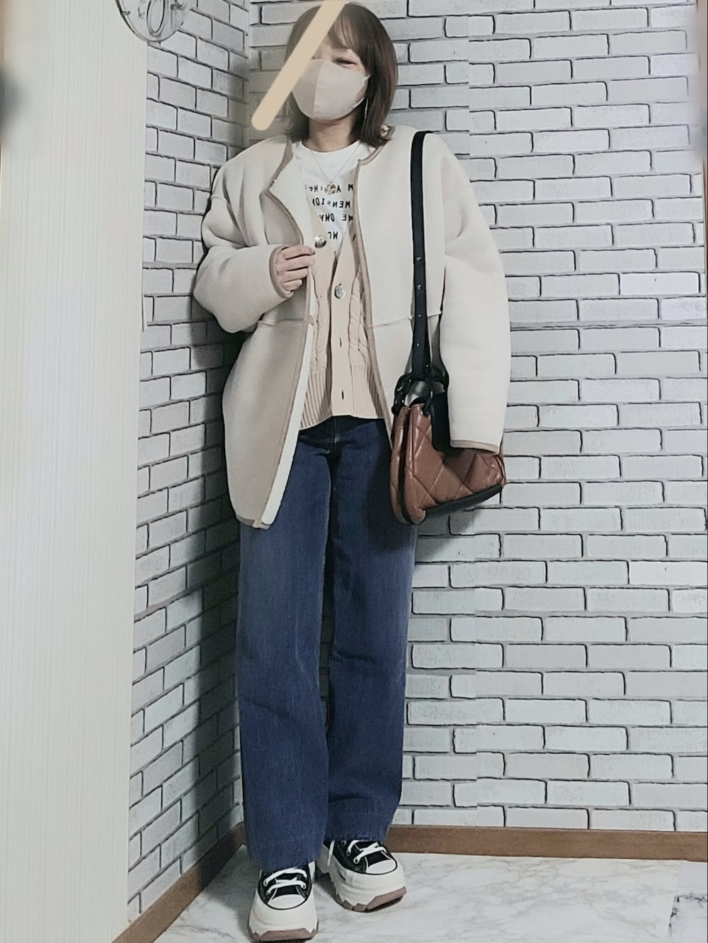 ベージュ系のカーディガン/ボレロ、ホワイト系のTシャツ/カットソー、ホワイト系のムートンコートを着用したレディースの冬コーディネートの2枚目の写真