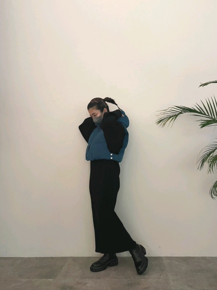 ブルー系のダウンベスト、ブラック系のワンピース、ブラック系のブーツを着用したレディースの夏コーディネートの8枚目の写真