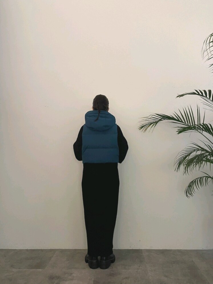 ブルー系のダウンベスト、ブラック系のワンピース、ブラック系のブーツを着用したレディースの夏コーディネートの2枚目の写真