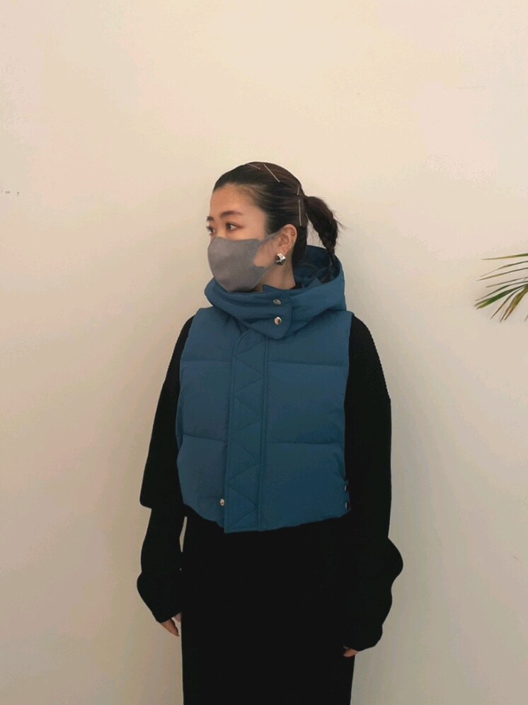 ブルー系のダウンベスト、ブラック系のワンピース、ブラック系のブーツを着用したレディースの夏コーディネートの3枚目の写真