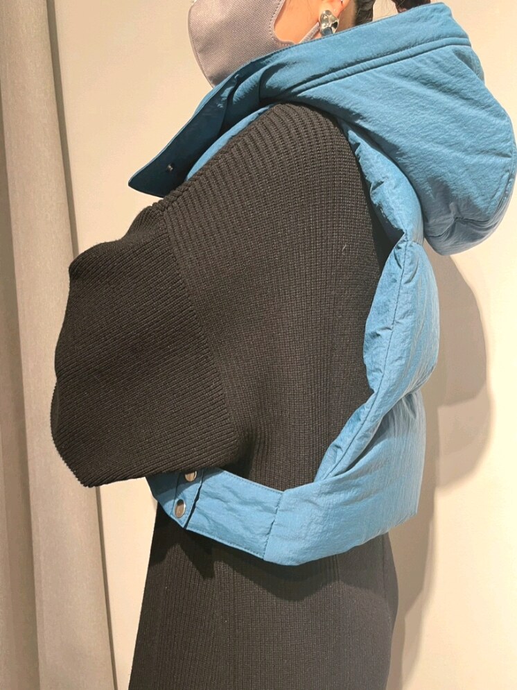 ブルー系のダウンベスト、ブラック系のワンピース、ブラック系のブーツを着用したレディースの夏コーディネートの6枚目の写真