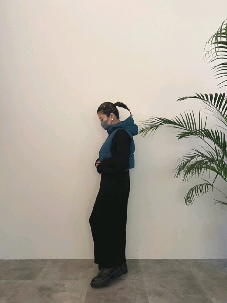 ブルー系のダウンベスト、ブラック系のワンピース、ブラック系のブーツを着用したレディースの夏コーディネートの7枚目の写真