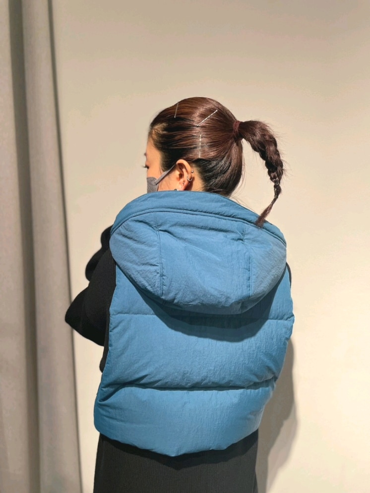 ブルー系のダウンベスト、ブラック系のワンピース、ブラック系のブーツを着用したレディースの夏コーディネートの5枚目の写真