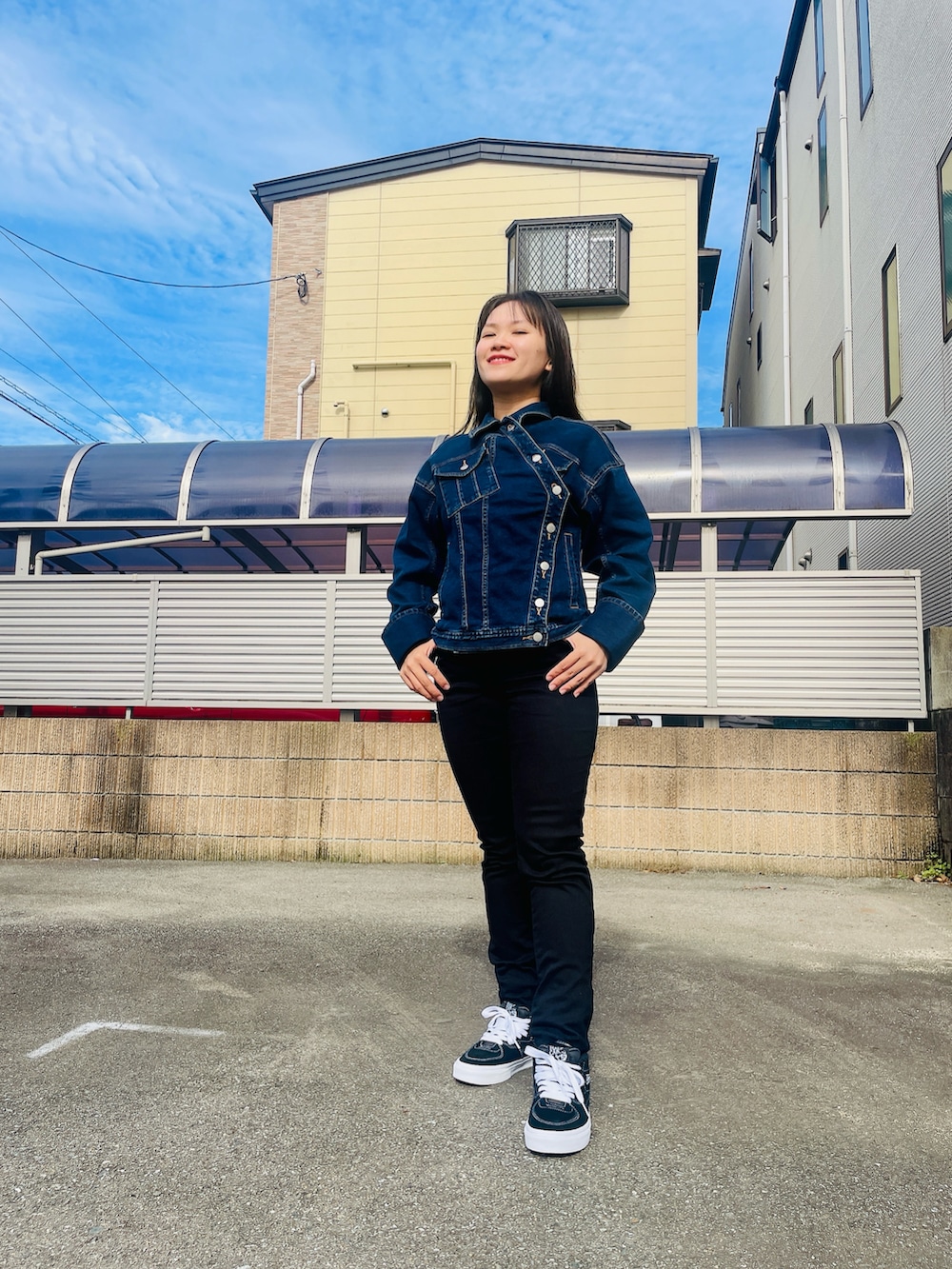 ブラック系のデニムパンツ、ブラック系のスニーカー、ブルー系のデニムジャケットを着用したレディースの秋コーディネートの2枚目の写真