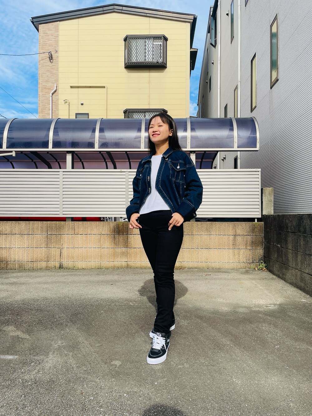 ブラック系のデニムパンツ、ブラック系のスニーカー、ブルー系のデニムジャケットを着用したレディースの秋コーディネートの3枚目の写真