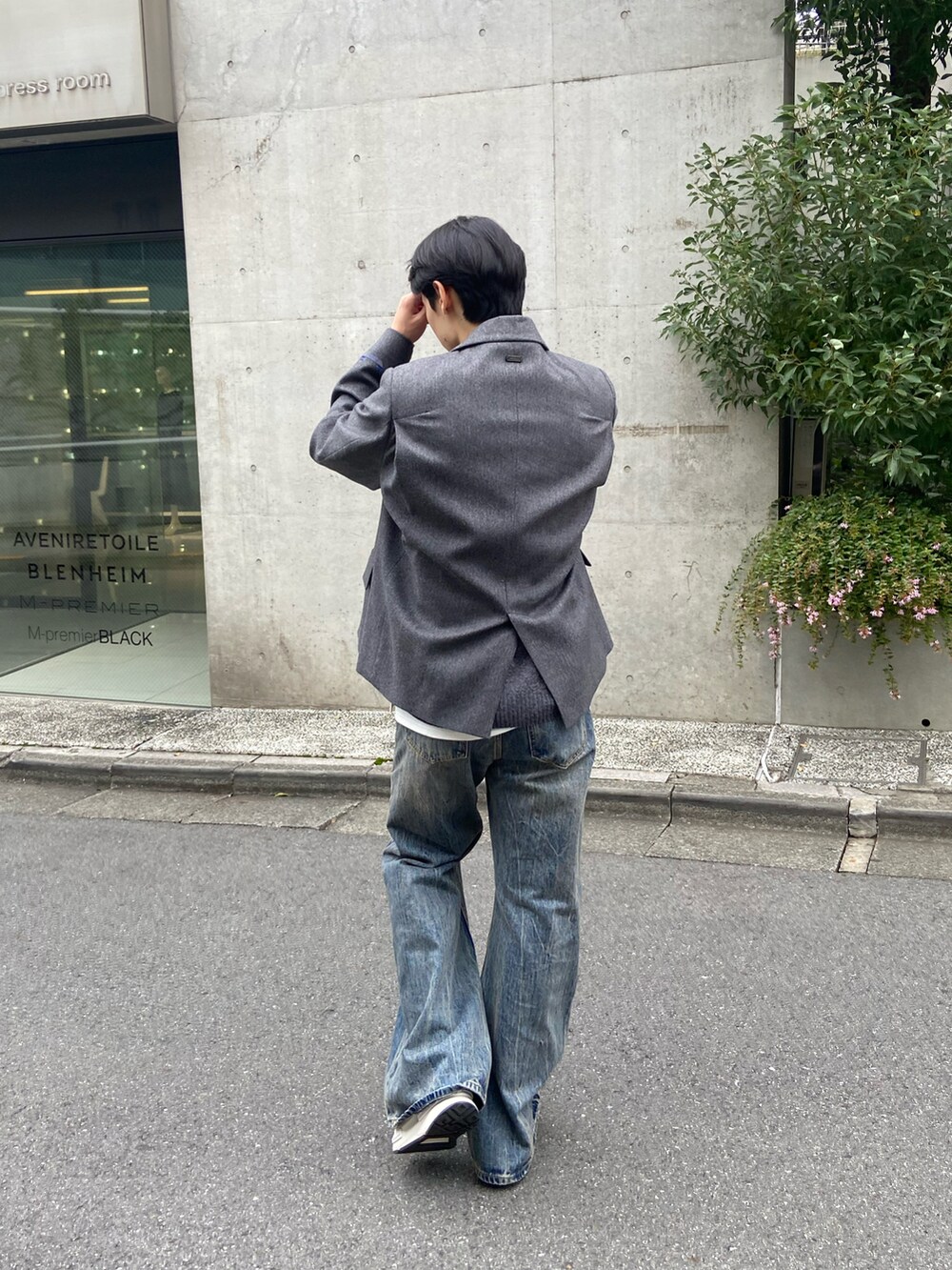 グレー系のテーラードジャケット、グレー系のニット/セーター、ブルー系のデニムパンツを着用したメンズの秋コーディネートの4枚目の写真