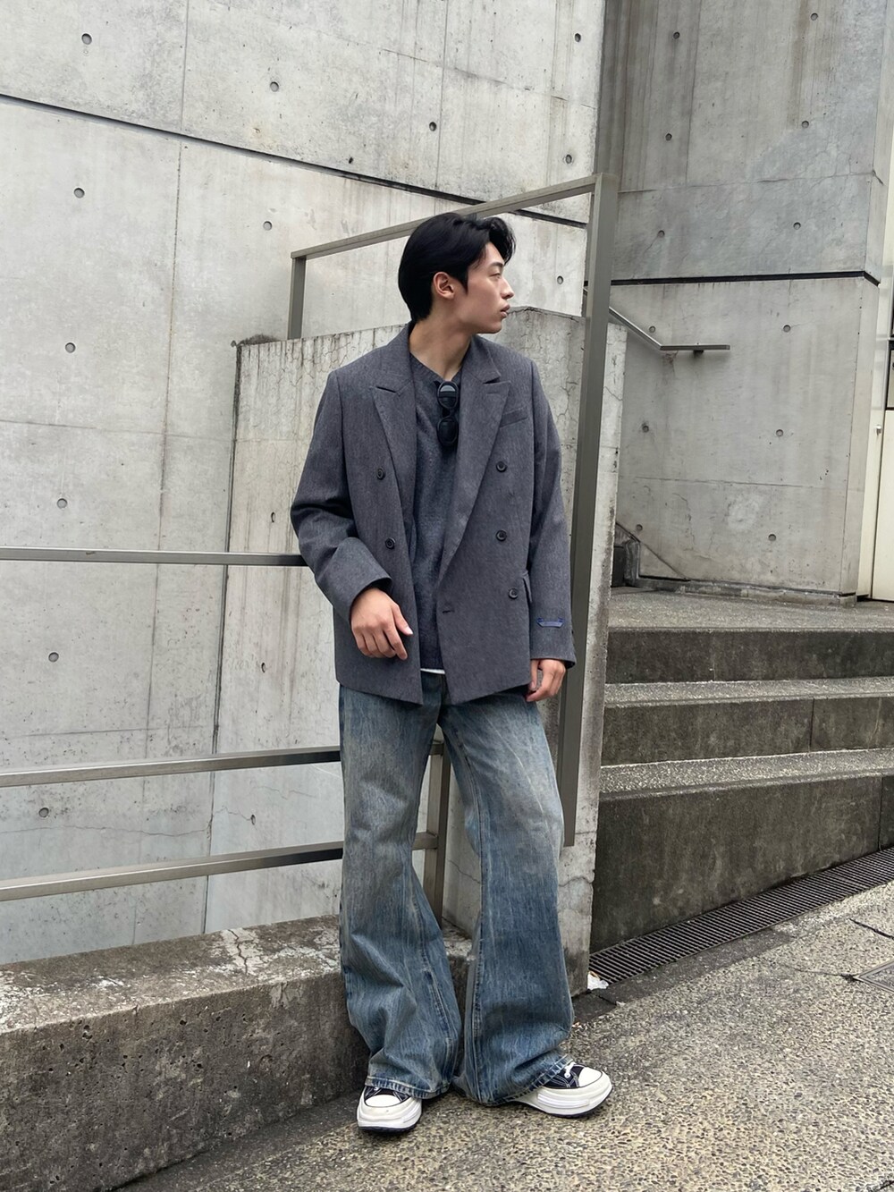 グレー系のテーラードジャケット、グレー系のニット/セーター、ブルー系のデニムパンツを着用したメンズの秋コーディネートの2枚目の写真