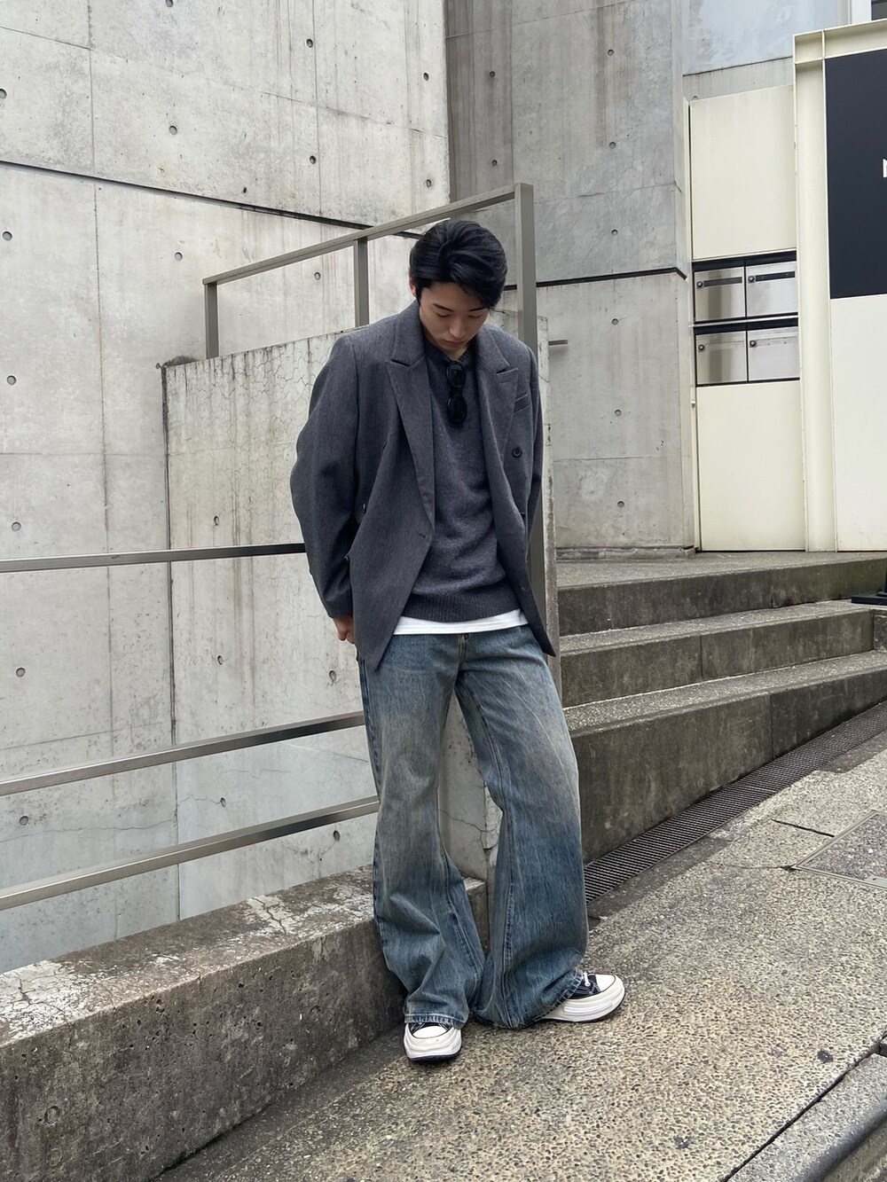 グレー系のテーラードジャケット、グレー系のニット/セーター、ブルー系のデニムパンツを着用したメンズの秋コーディネートの3枚目の写真