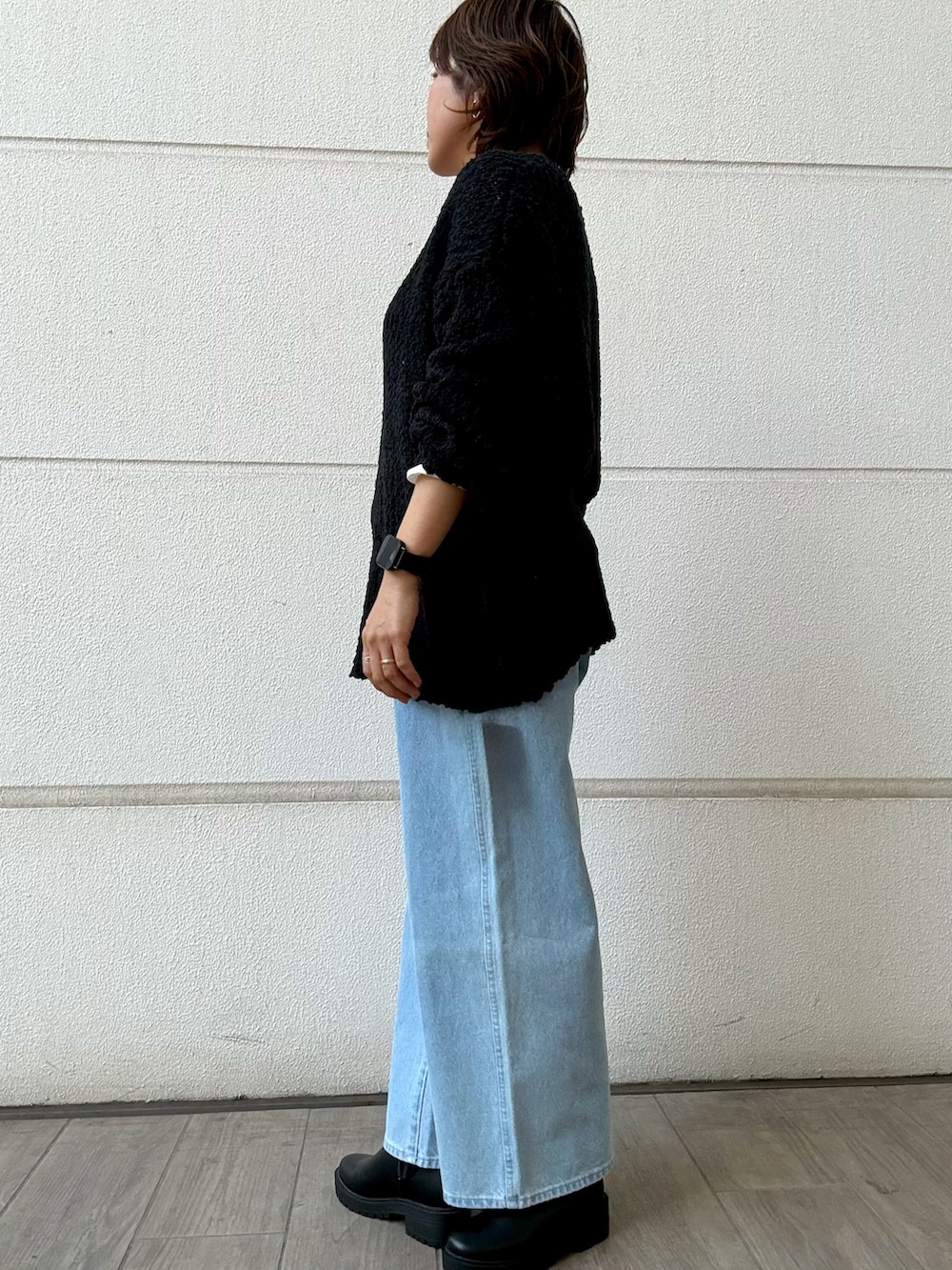 ブラック系のニット/セーター、ブルー系のデニムパンツ、ブラック系のブーツを着用したレディースの冬コーディネートの2枚目の写真