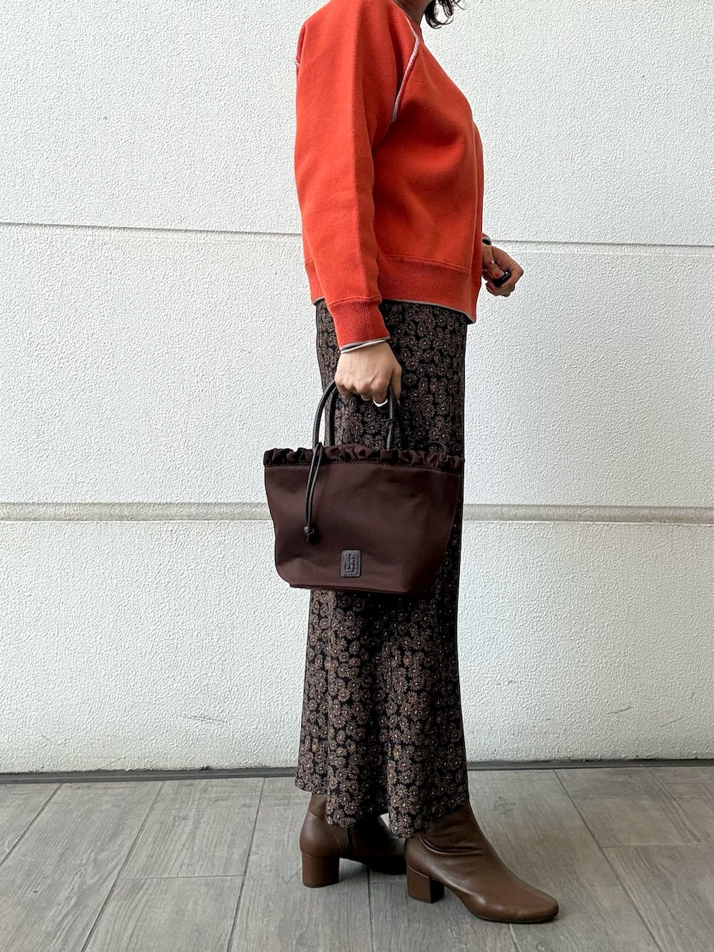 オレンジ系のスカート、ブラウン系のトートバッグ、オレンジ系のニット/セーターを着用したレディースの冬コーディネートの2枚目の写真