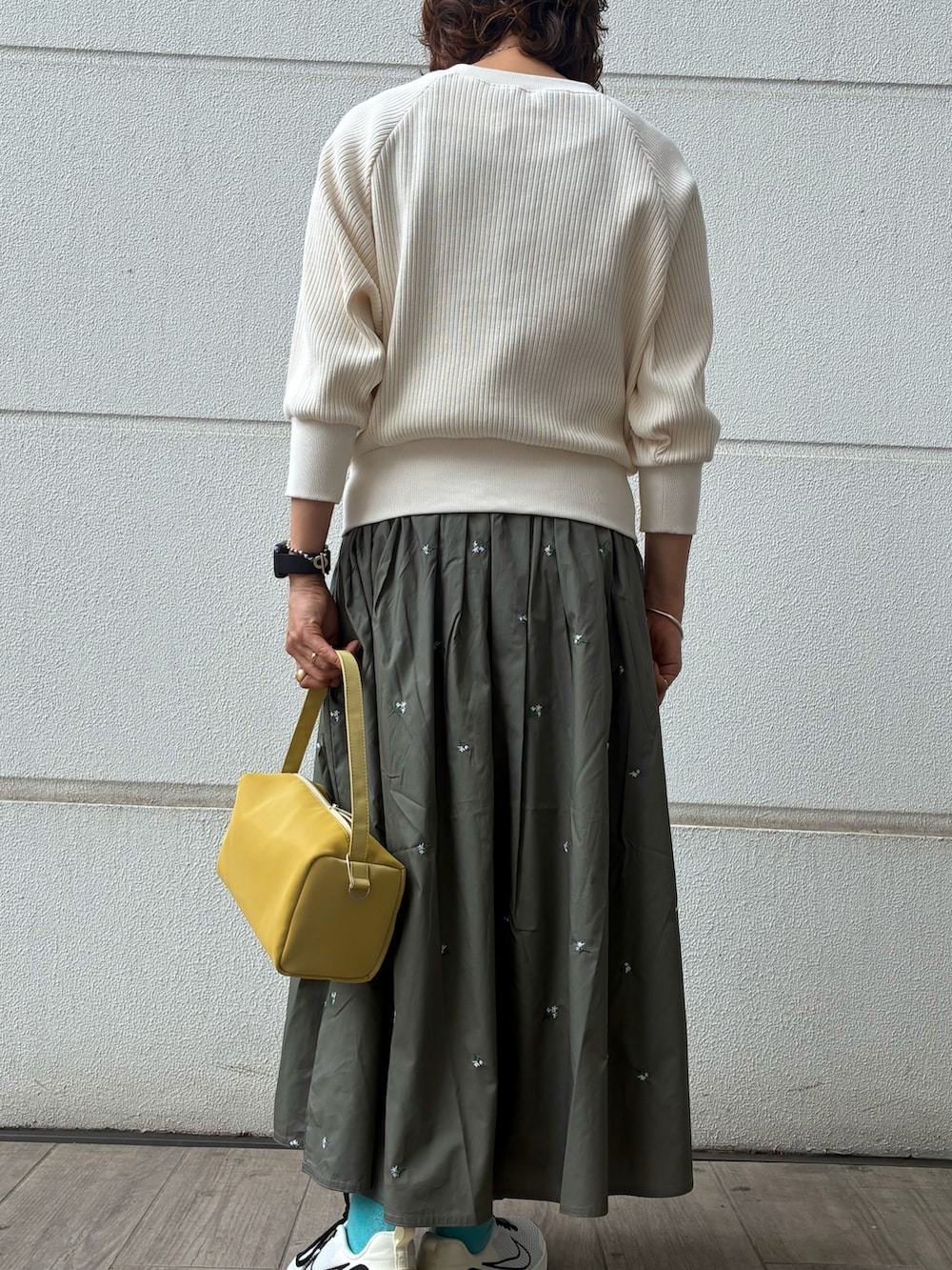 グリーン系のスカート、ホワイト系のカーディガン/ボレロ、イエロー系のトートバッグを着用したレディースの春コーディネートの2枚目の写真