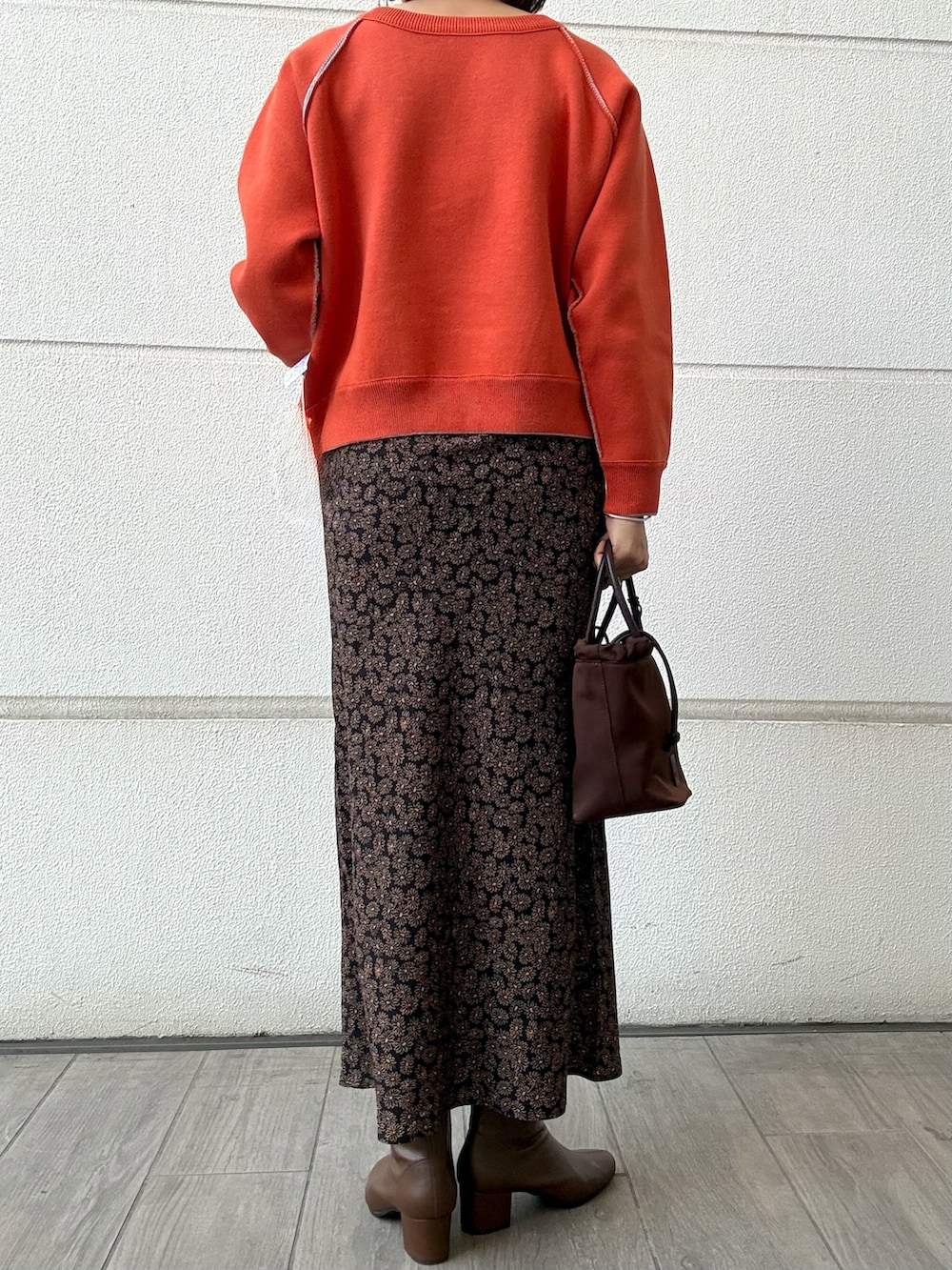 オレンジ系のスカート、ブラウン系のトートバッグ、オレンジ系のニット/セーターを着用したレディースの冬コーディネートの3枚目の写真