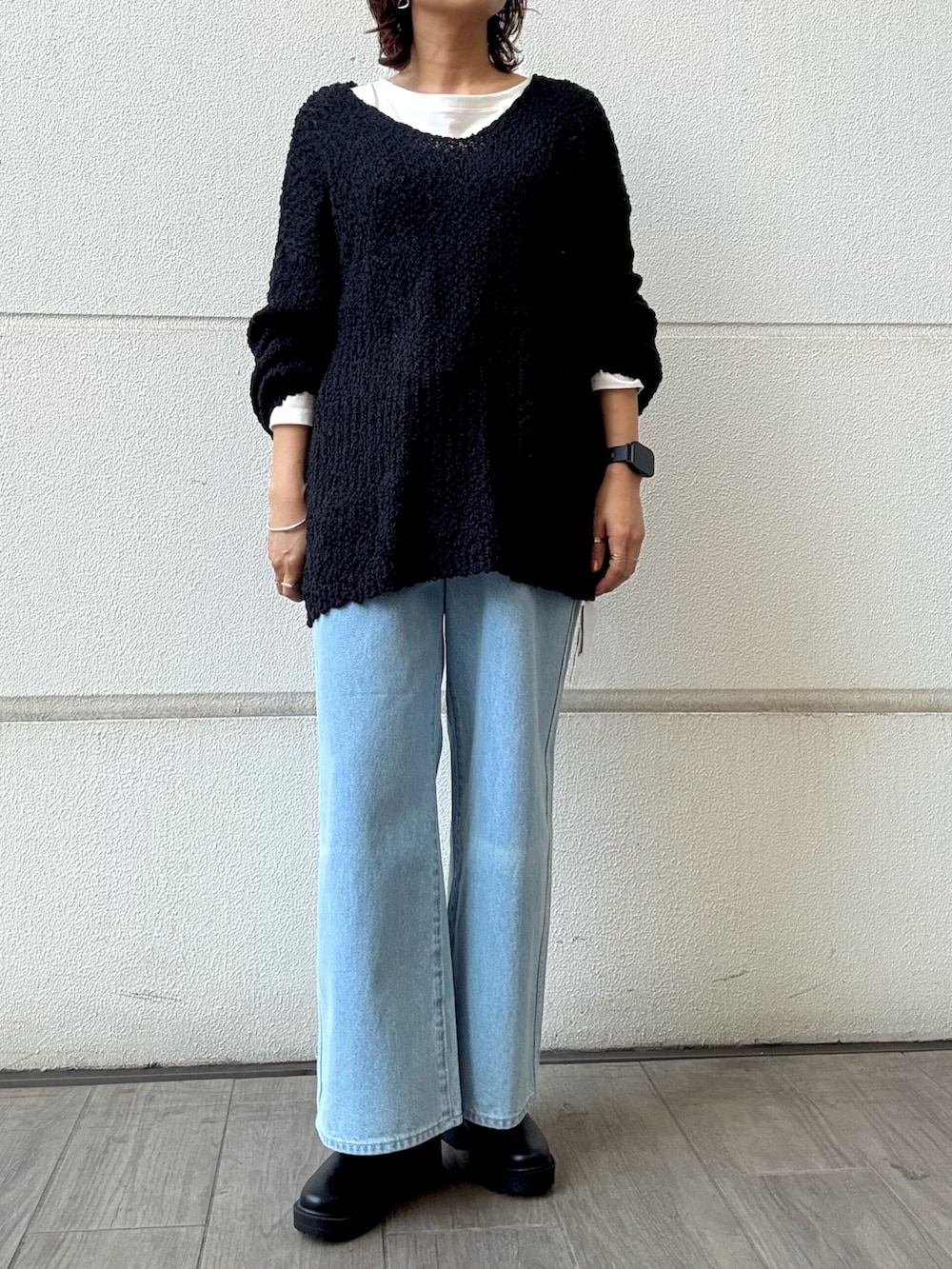 ブラック系のニット/セーター、ブルー系のデニムパンツ、ブラック系のブーツを着用したレディースの冬コーディネートの3枚目の写真