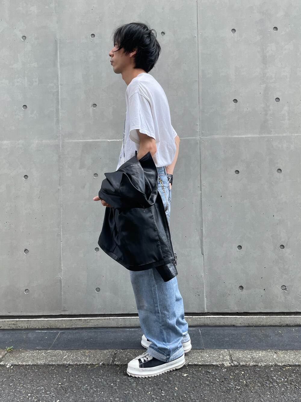 ブラック系のライダースジャケット、ブルー系のデニムパンツ、ブラック系のスニーカーを着用したメンズの夏コーディネートの6枚目の写真