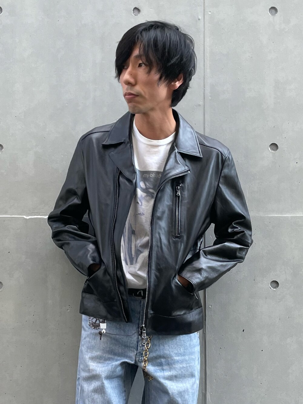 ブラック系のライダースジャケット、ブルー系のデニムパンツ、ブラック系のスニーカーを着用したメンズの夏コーディネートの2枚目の写真