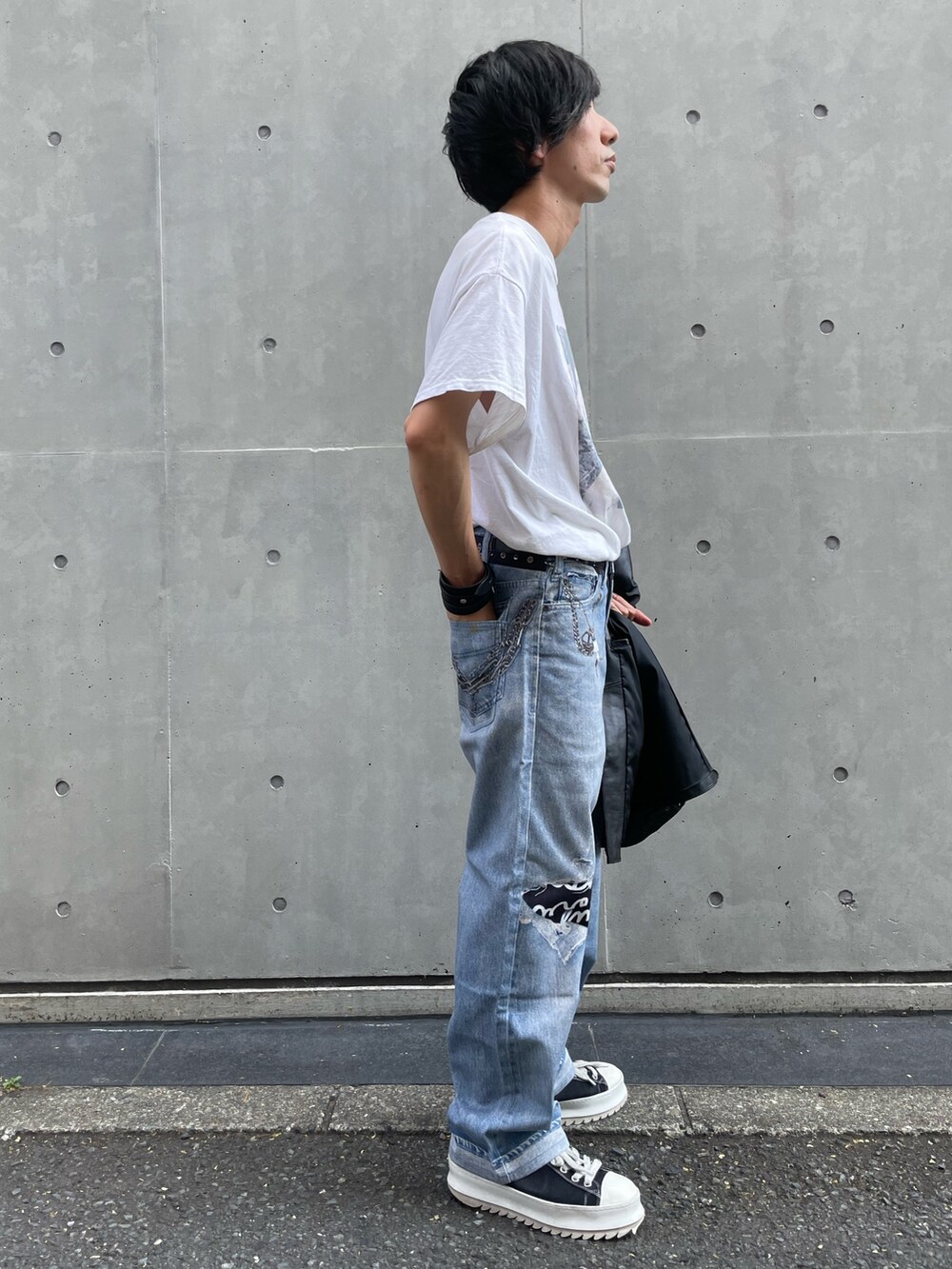 ブラック系のライダースジャケット、ブルー系のデニムパンツ、ブラック系のスニーカーを着用したメンズの夏コーディネートの4枚目の写真