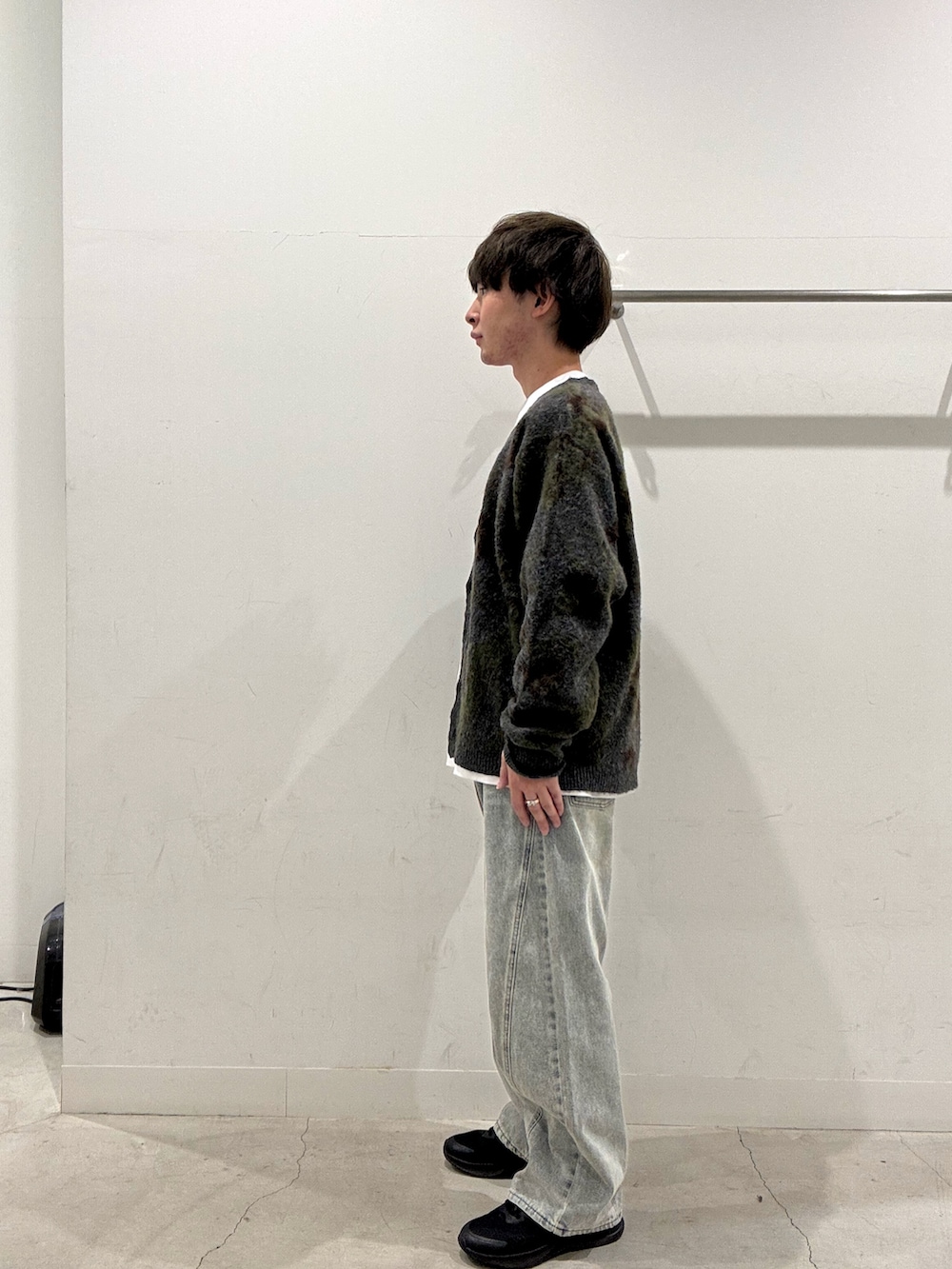 グリーン系のニット/セーター、ホワイト系のTシャツ/カットソー、ブルー系のデニムパンツを着用したメンズの秋コーディネートの2枚目の写真