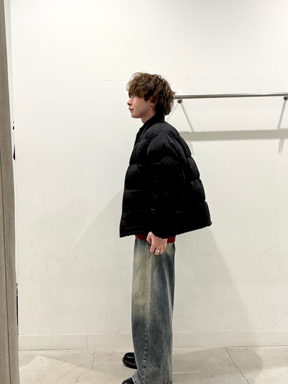 レッド系のスウェット、ブラック系のブルゾン、ブルー系のデニムパンツを着用したメンズの秋コーディネートの2枚目の写真