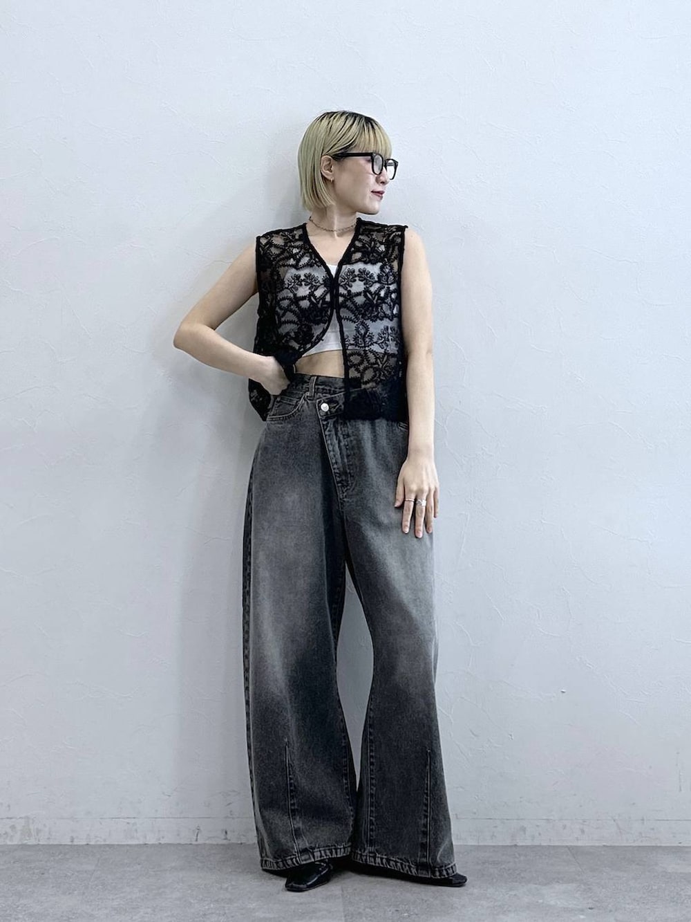グレー系のデニムパンツ、ブラック系のベスト、ホワイト系のブラジャーを着用したレディースの夏コーディネートの2枚目の写真