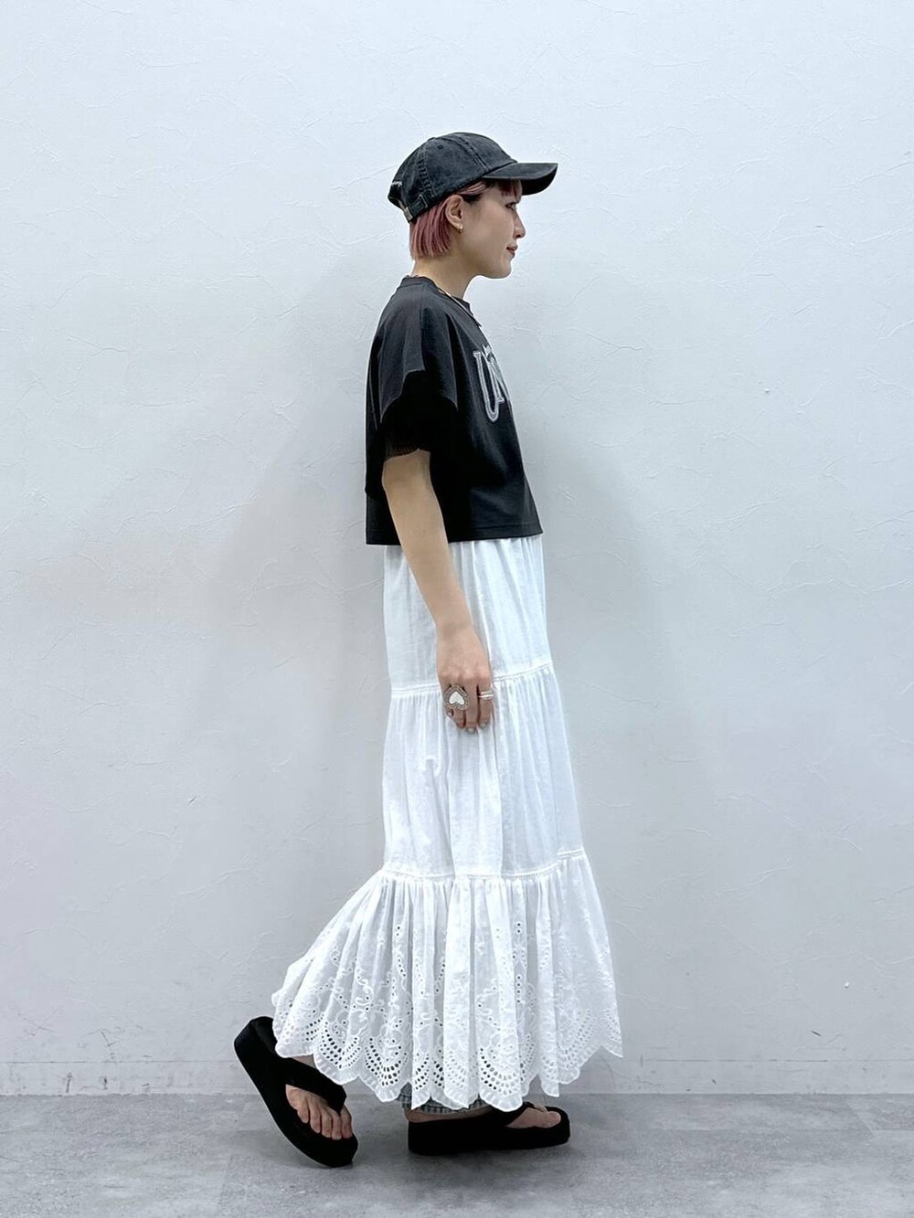 ブルー系のデニムパンツ、ブラック系のTシャツ/カットソー、ホワイト系のスカートを着用したレディースの春コーディネートの4枚目の写真