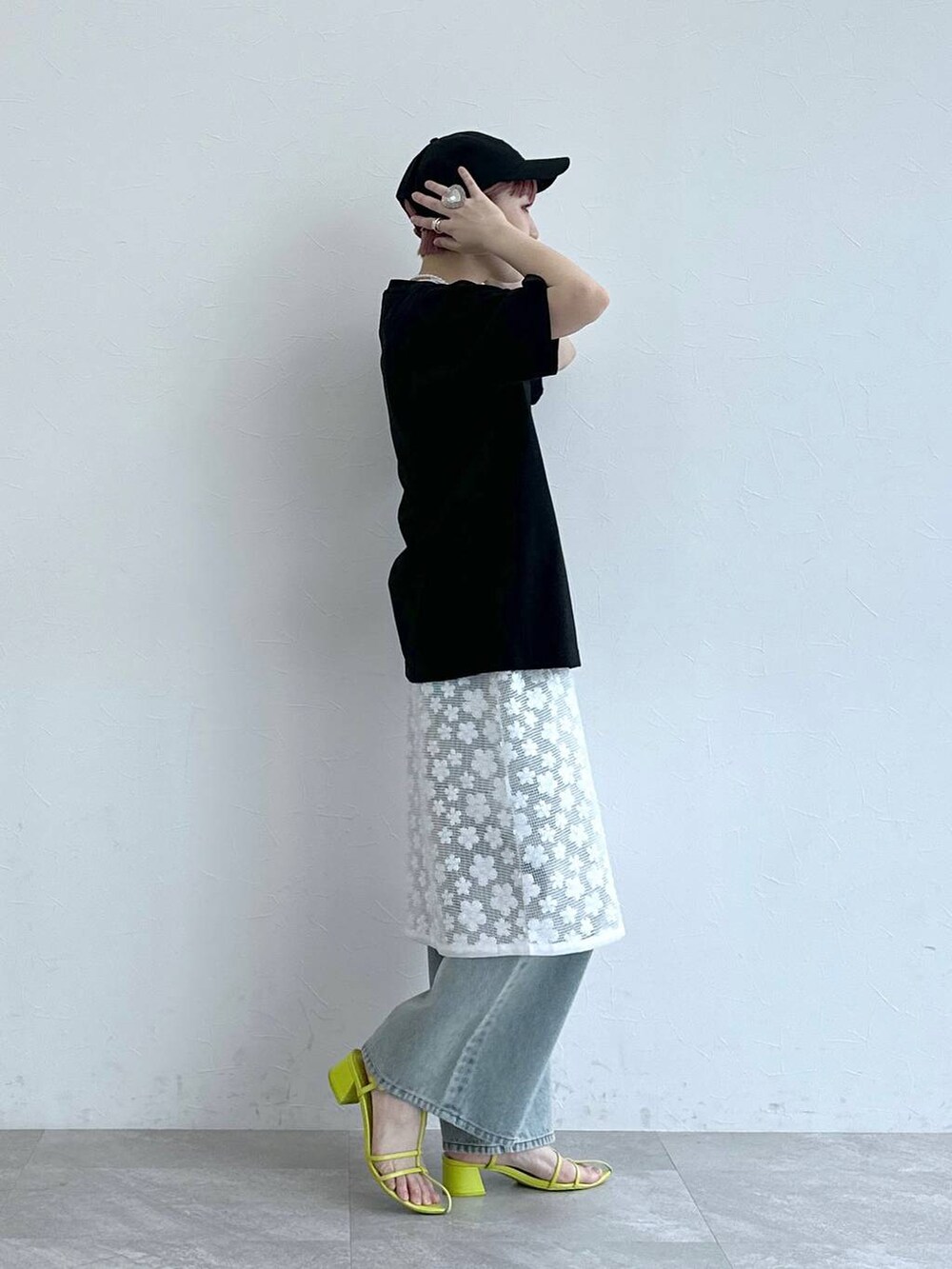 ブルー系のデニムパンツ、ホワイト系のワンピース、ブラック系のTシャツ/カットソーを着用したレディースの春コーディネートの6枚目の写真