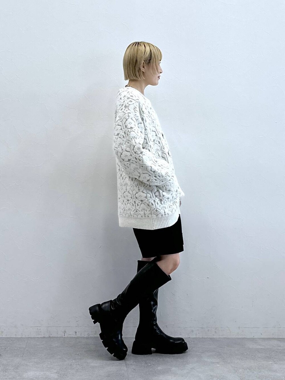 ブラック系のブーツ、ホワイト系のカーディガン/ボレロ、ブラック系のチノパンツを着用したレディースの秋コーディネートの4枚目の写真