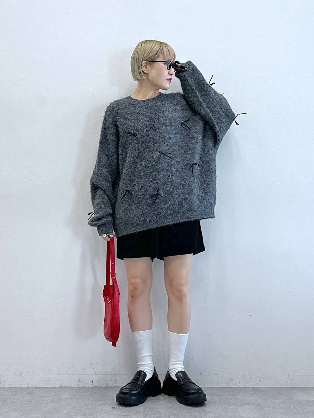 ブラック系のチノパンツ、レッド系のショルダーバッグ、グレー系のニット/セーターを着用したレディースの冬コーディネートの3枚目の写真